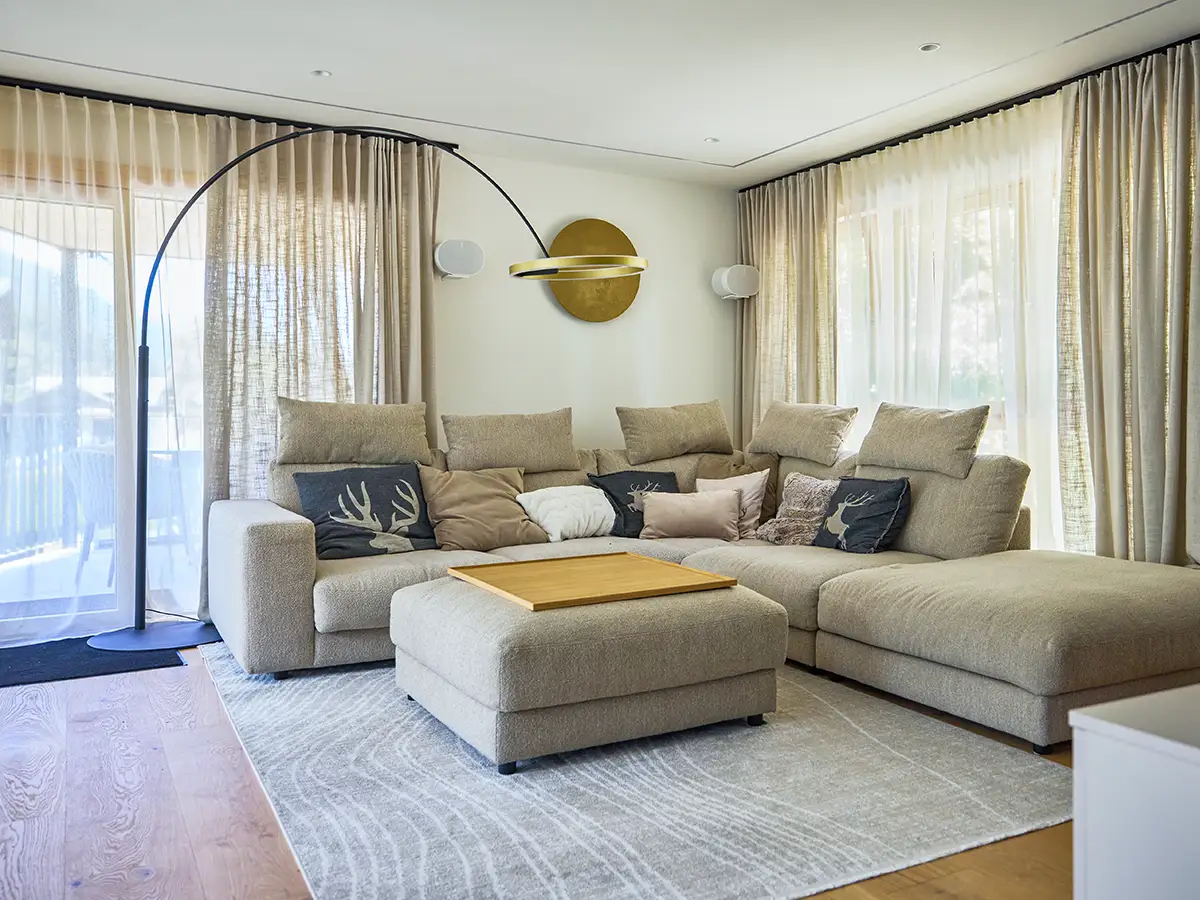 Heller Wohnbereich mit Sofa und großen Fenstern im Apartment HENRI im Chalet H