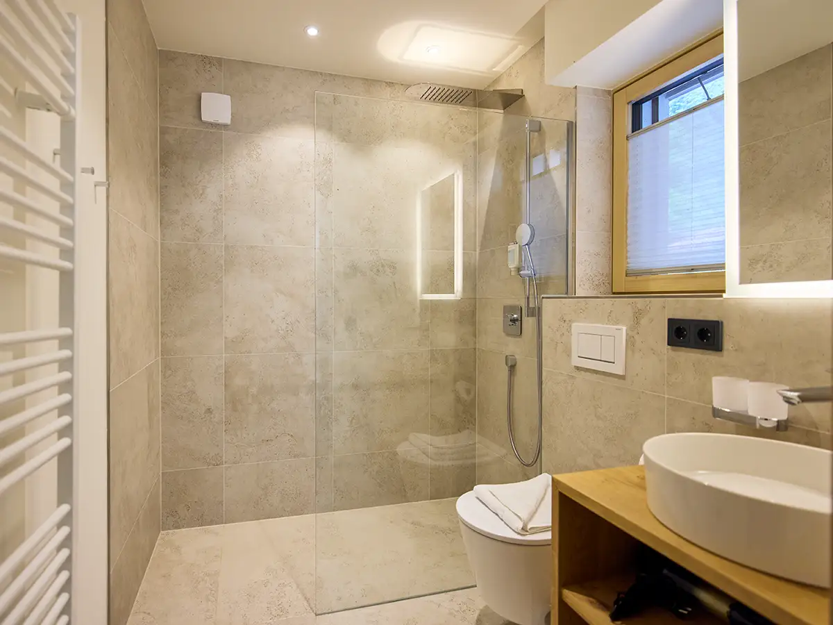 Modernes Tageslichtbad mit bodengleicher Dusche und Naturtönen im Apartment HANNI im Chalet H