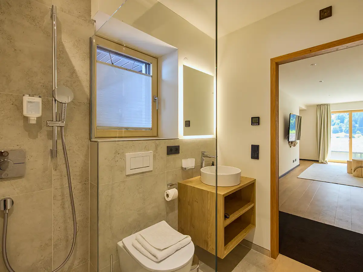 Helles Badezimmer mit Fenster, Waschtisch und moderner Dusche im Apartment HANNI im Chalet H