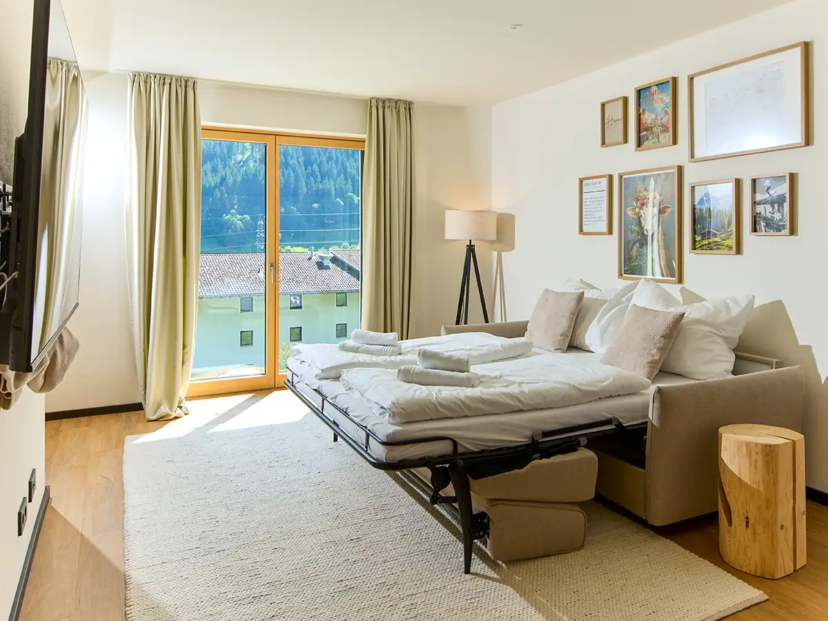 Gemütlicher Wohnbereich mit Schlafsofa und Zugang zur Terrasse im Apartment HANNI im Chalet H