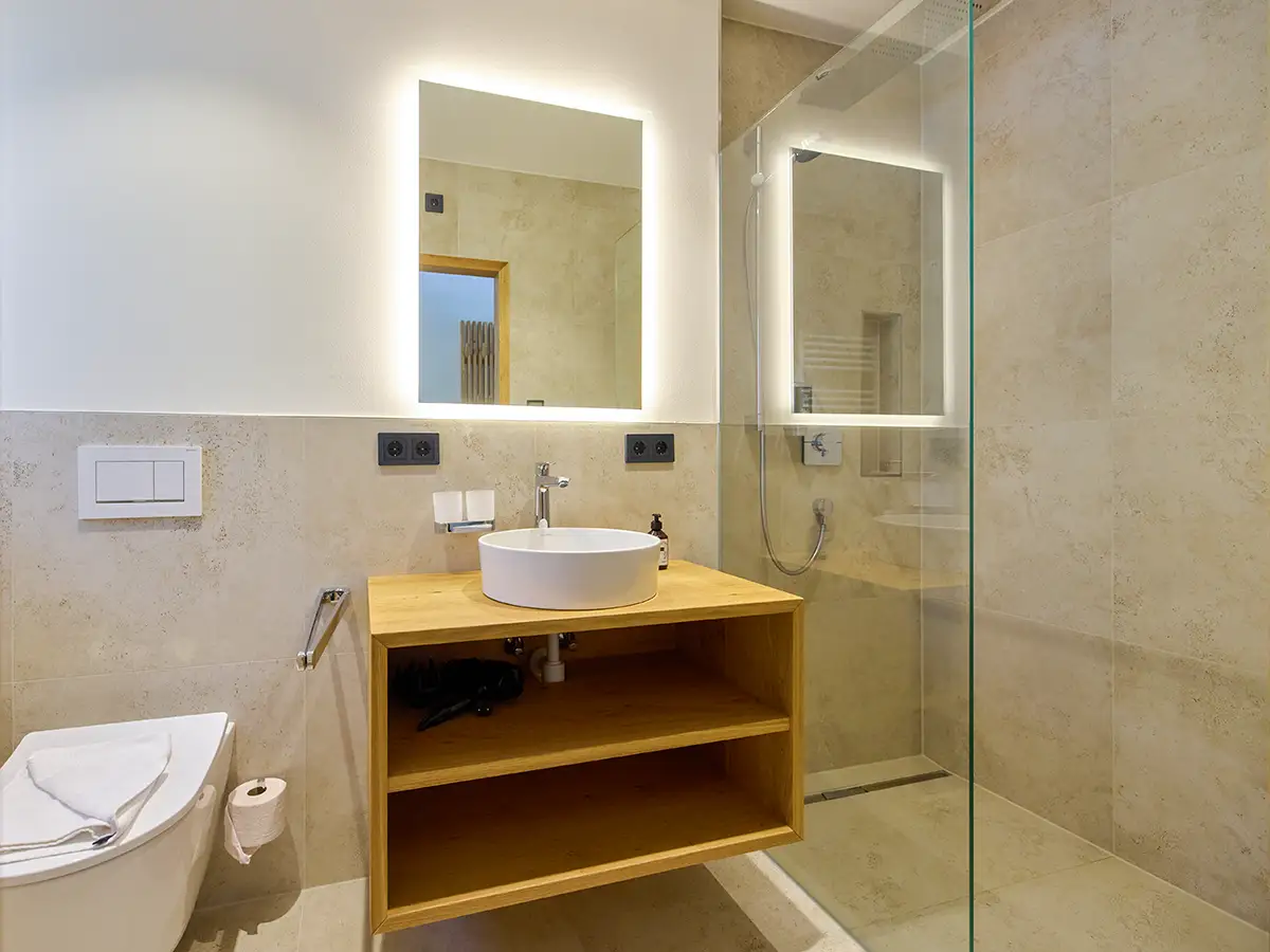 Helles Badezimmer mit Holzwaschtisch und großer Glasdusche im Apartment HANSI im Chalet H