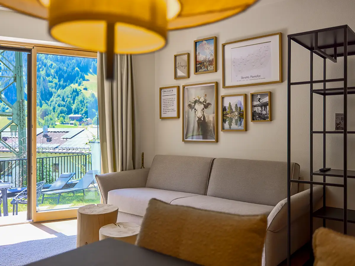 Gemütlicher Wohnraum mit Sofa, Bilderwand und Zugang zur Terrasse im Apartment HANSI im Chalet H