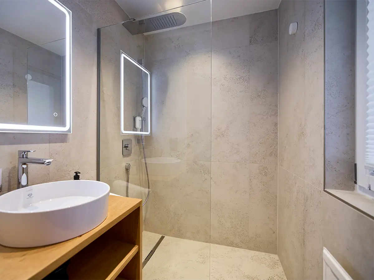Modernes Badezimmer mit beleuchtetem Spiegel und Dusche im Apartment HARMONY im Chalet H