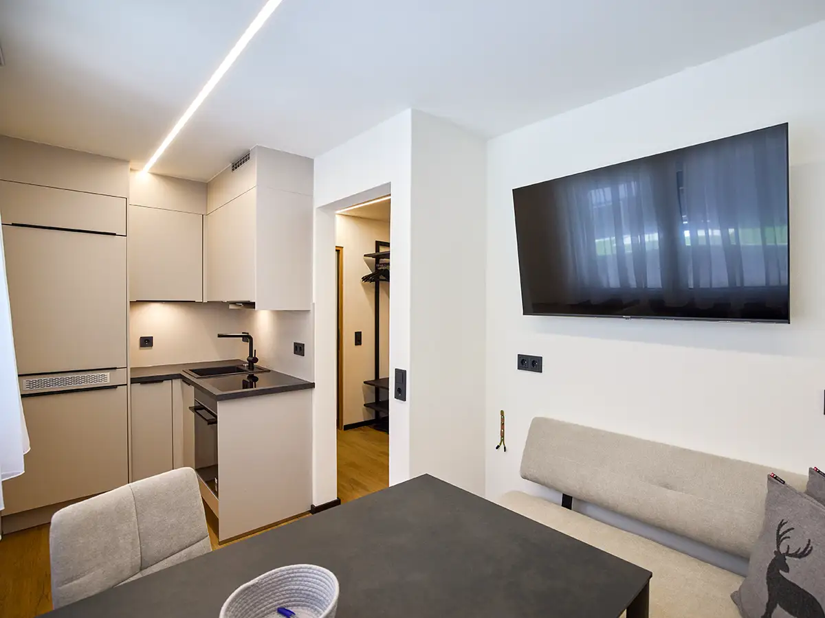 Offener Essbereich mit angrenzender Küche und TV im Apartment HARMONY im Chalet H