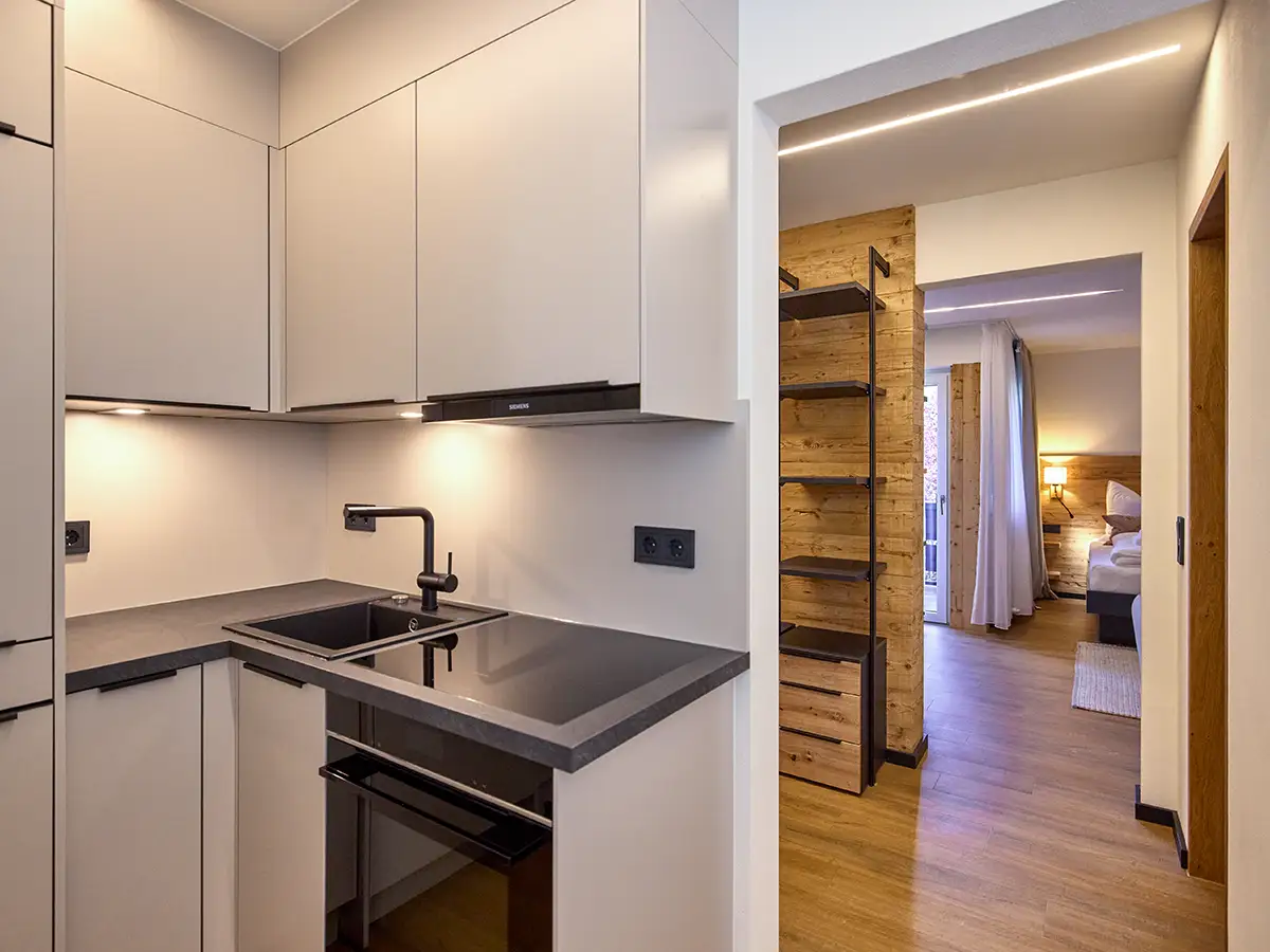 Kompakte Küche mit Blick in den hellen Apartmentflur im Apartment HARMONY im Chalet H