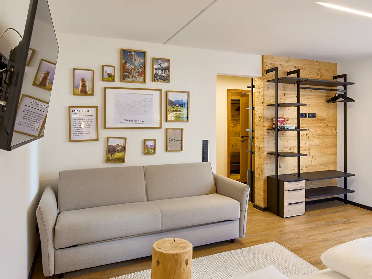 Schlafzimmer mit Bilderwand, Sofa und offenem Regal im Apartment HARMONY im Chalet H