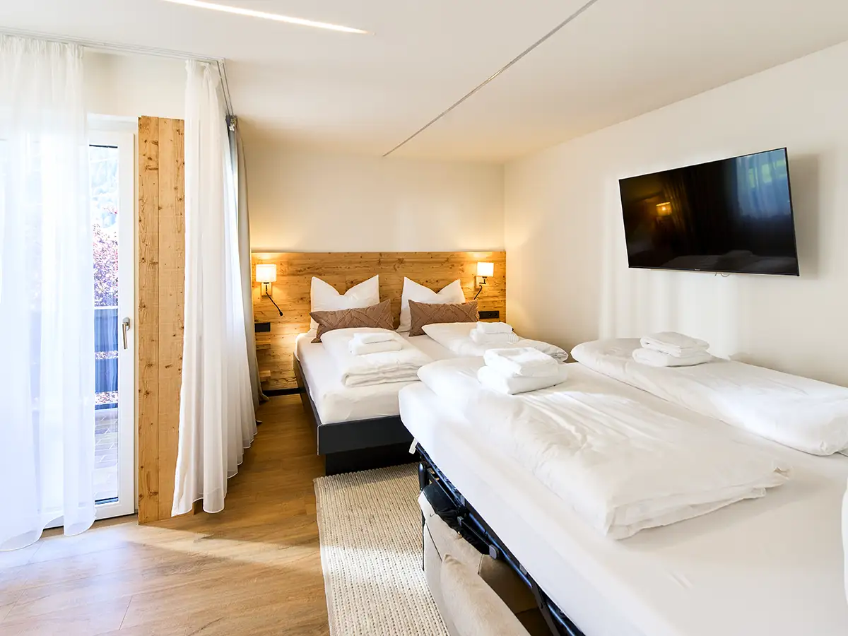 Helles Schlafzimmer mit Doppelbett und zusätzlicher Schlafmöglichkeit im Apartment HARMONY im Chalet H