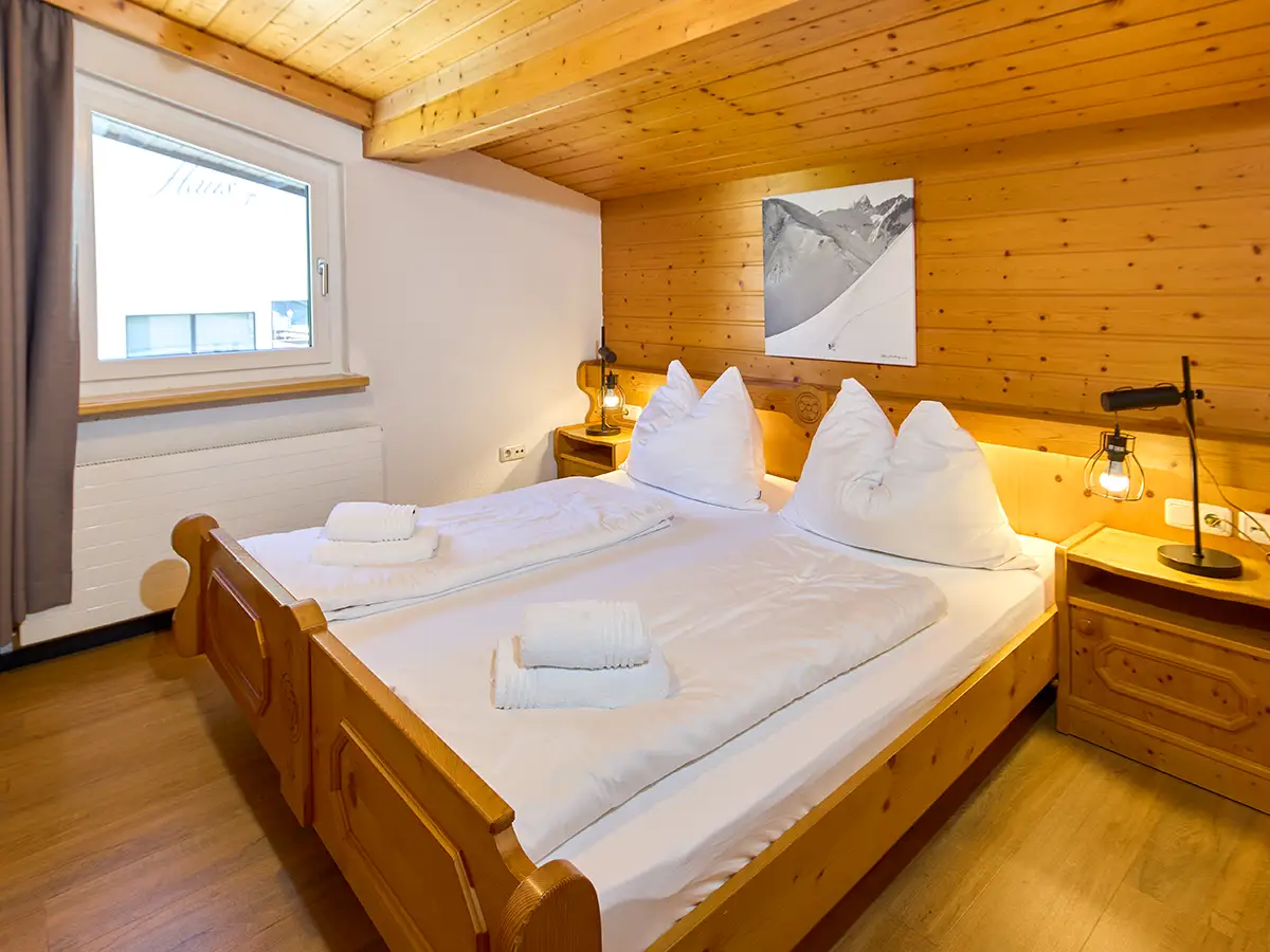 Alpines Doppelzimmer mit Holzdecke und heller Bettwäsche im Apartment HEAVEN im Chalet H