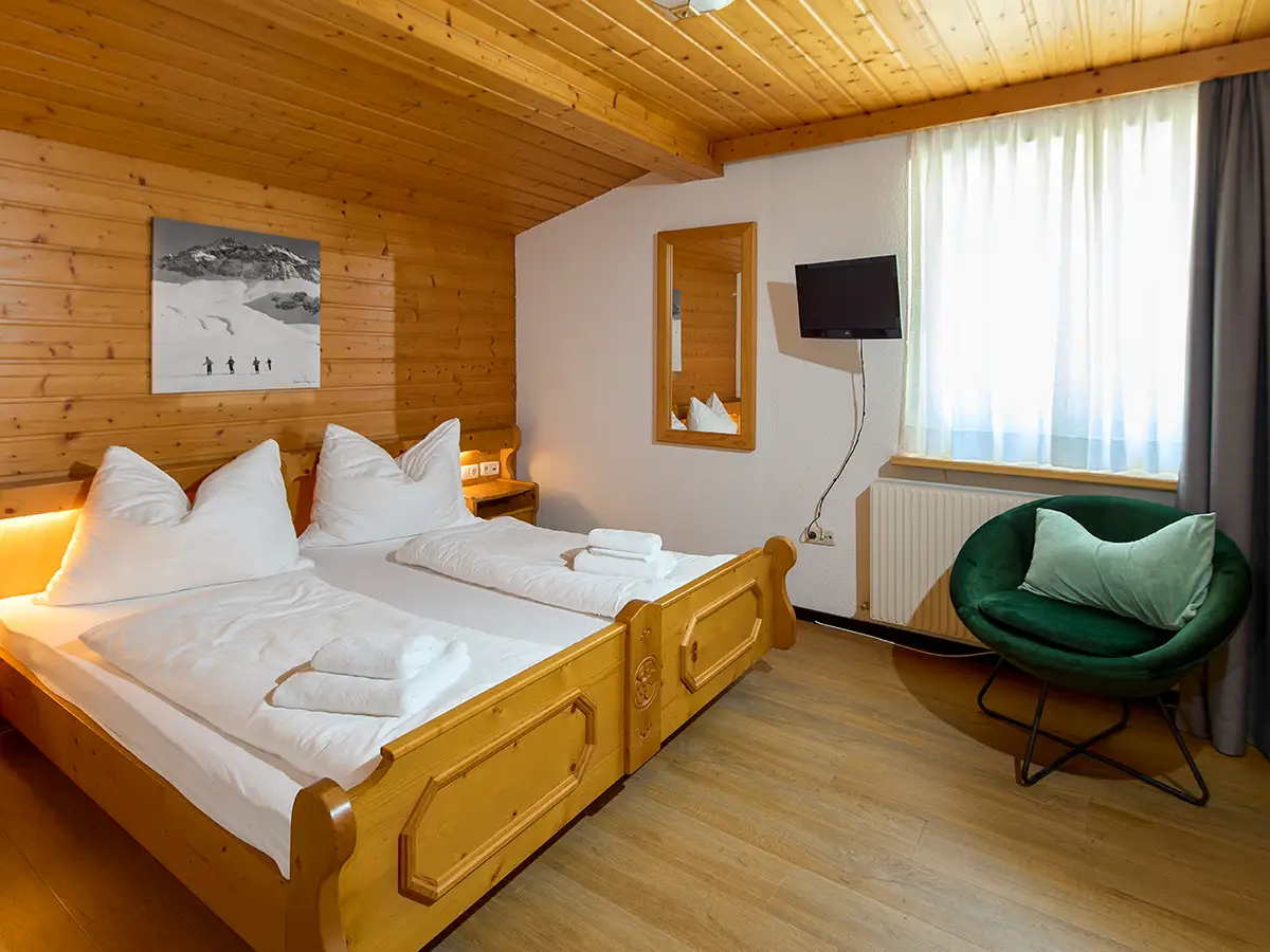 Gemütliches Doppelzimmer mit Holzdecke und kleiner Sitzecke im Apartment HEAVEN im Chalet H