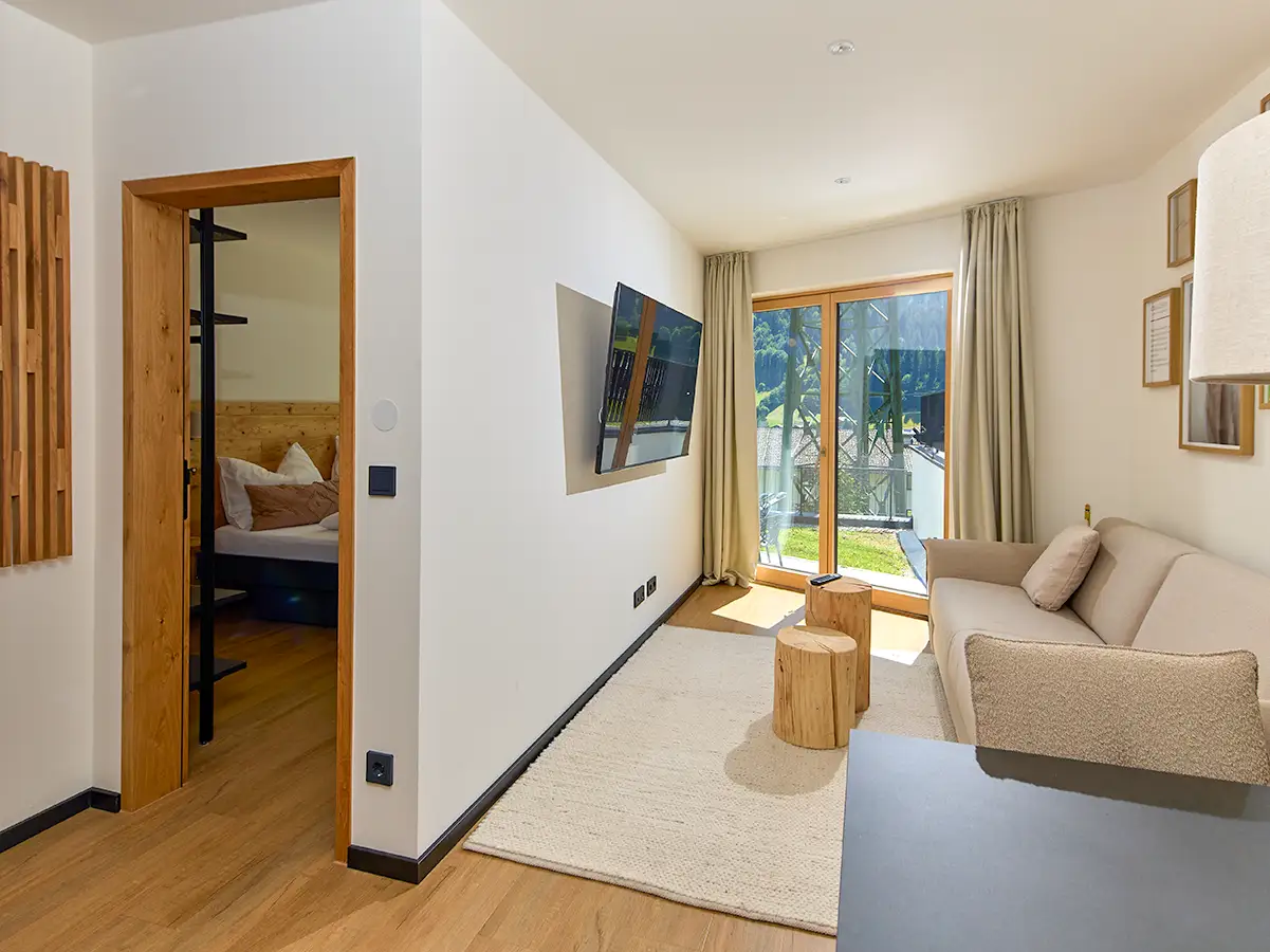 Offener Wohn- und Schlafbereich mit Sofa und Zugang ins Grüne im Apartment HEIDI im Chalet H