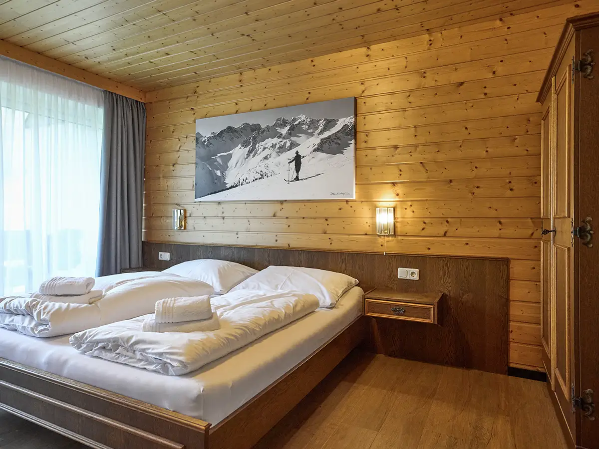 Behagliches Doppelzimmer mit holzverkleideter Wand im Apartment HOME im Chalet H