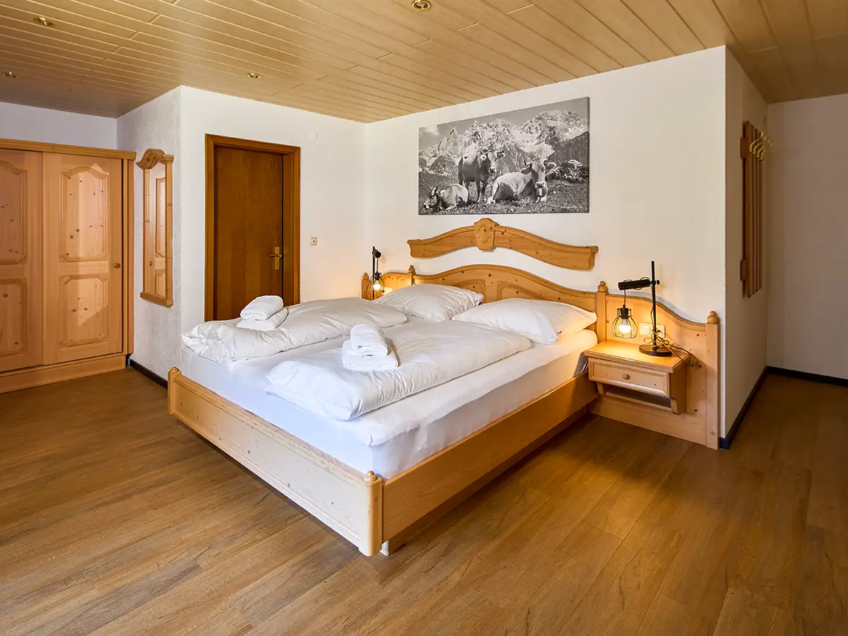Komfortables Doppelzimmer mit Holzdetails und Nachttischen im Apartment HOME im Chalet H