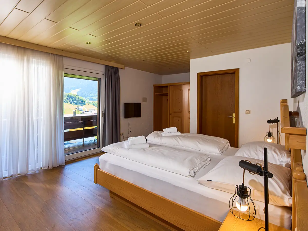 Helles Doppelzimmer mit Holzelementen und Blick nach draußen im Apartment HOME im Chalet H
