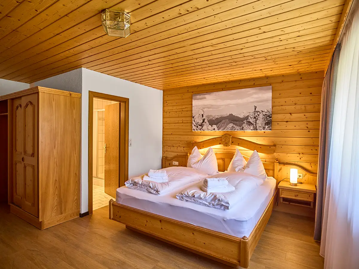 Alpines Doppelzimmer mit viel Holz und Wandbild im Apartment HOME im Chalet H