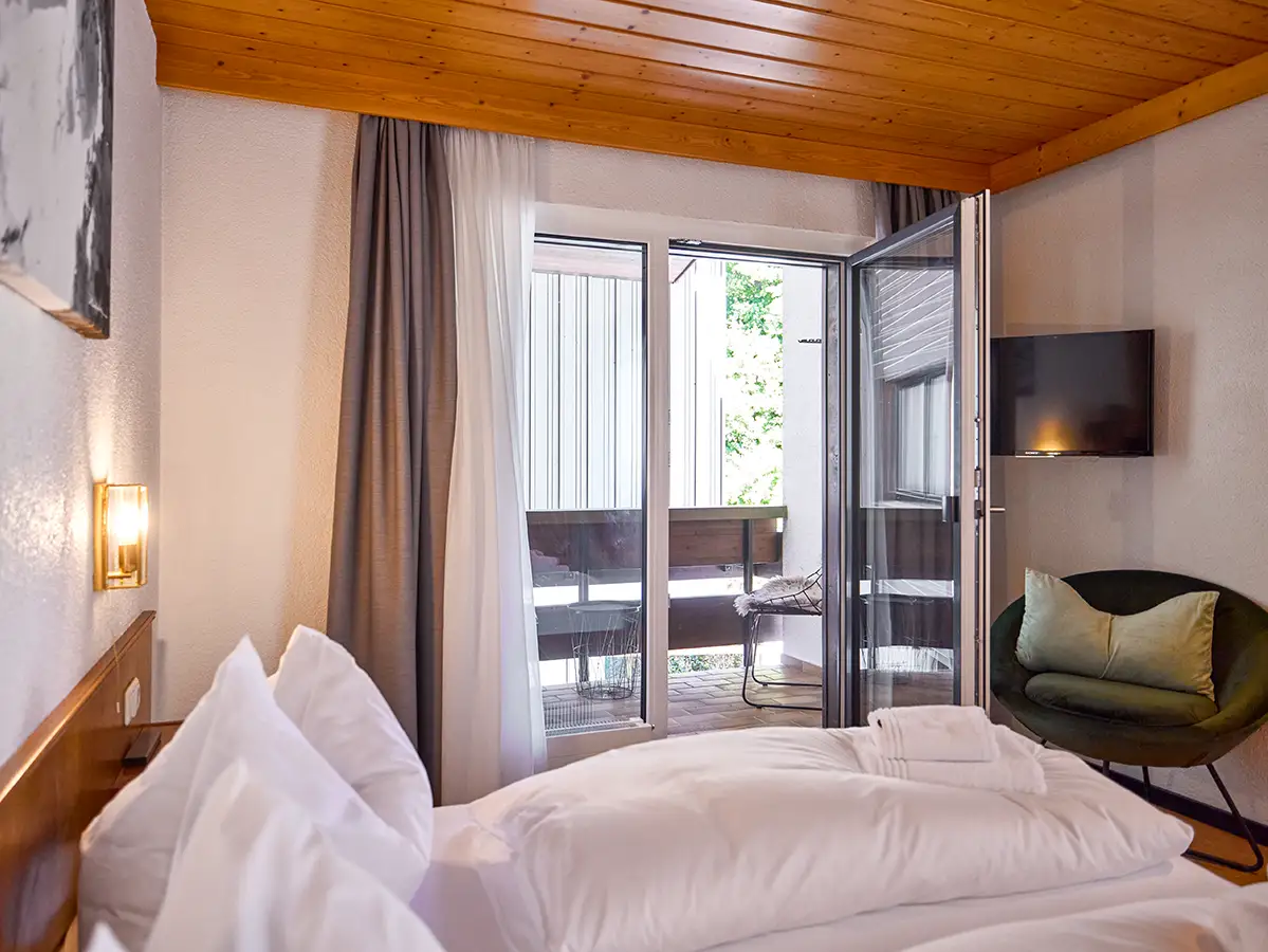 Doppelzimmer mit Holzdecke und großem Fenster im Apartment HOME im Chalet H